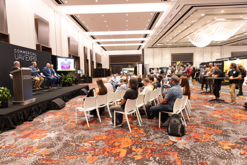 a group of people watching a presentation on the show floor at Commercial UAV Expo